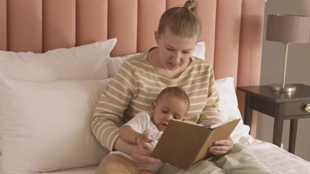 Mediana Larga Mujer Rubia Caucásica Sentada Cama Leyendo Libro Bebé — Vídeos de Stock