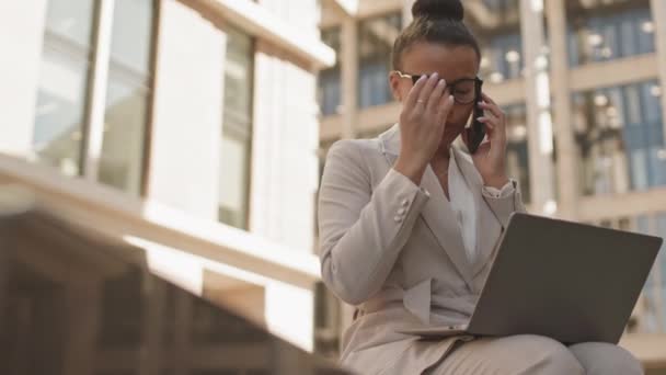 在城市环境中 有信心 有吸引力的女商人一边在户外笔记本电脑上工作一边打电话 速度中等程度地放慢 — 图库视频影像