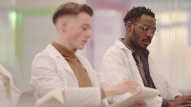 Modern konferans salonunda ders verirken Afro-Amerikalı sınıf arkadaşına yardım eden genç bir tıp öğrencisi orta derecede yavaşladı.