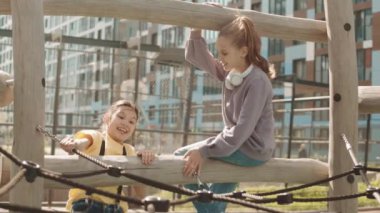 İki okul arkadaşının yazın okul bahçesinde çocuk parkına tırmanırken eğlendiği yavaş çekim.