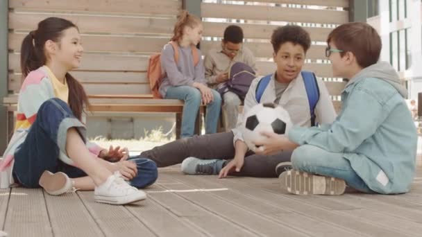 多族裔同学在课间或课后坐在学校操场上打篮球的慢镜头 — 图库视频影像