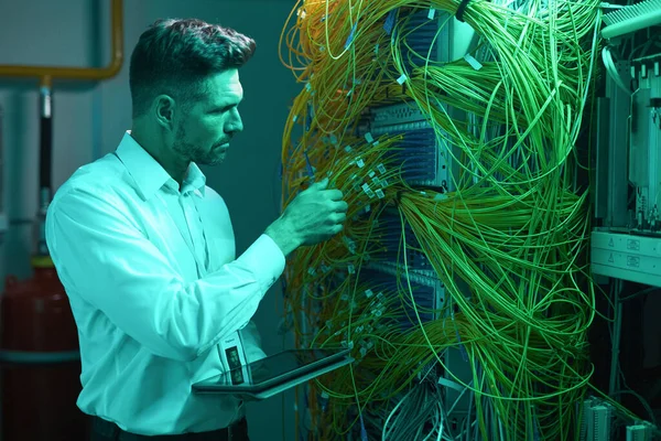 Mann richtet Netzwerk im Serverraum ein — Stockfoto