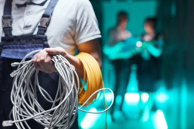 Close up of network engineer holding cables in server room during maintenance work in data center, copy space clipart