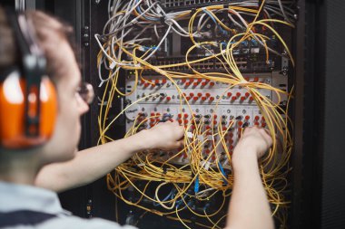 Close up of young network engineer connecting cables in server room during maintenance work in data center, copy space