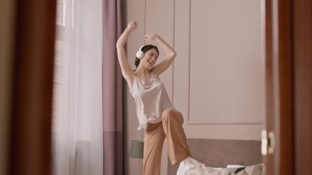 Запертая Молодая Белая Женщина Пижаме Наушниках Прыгающая Кровати Своей Комнате — стоковое видео