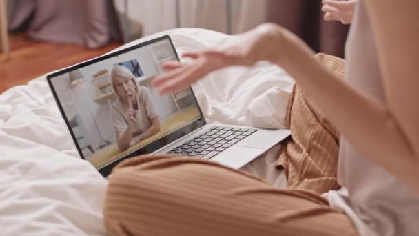 困住了一个无法辨认的人 他坐在床上 在便携式计算机上与白人老年妇女举行视频会议 — 图库视频影像