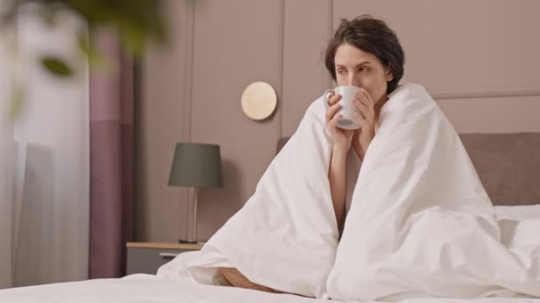 Γεμάτη Καστανομάτα Λευκή Γυναίκα Που Κάθεται Στο Κρεβάτι Καλυμμένη Κουβέρτα — Αρχείο Βίντεο