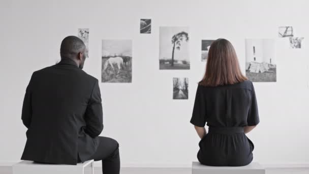 Beyaz Kadın Afrikalı Bir Adamın Sanat Galerisindeki Taburelerde Oturup Fotoğraf — Stok video