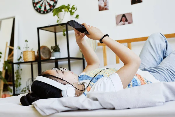 Дівчина-підліток використовує смартфон на ліжку — стокове фото