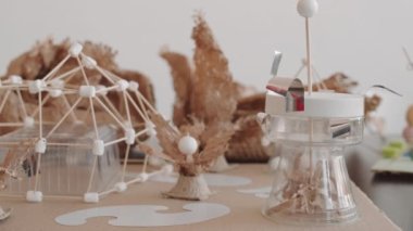 Masanın sol tarafında kağıt, mukavva ve çocuklar tarafından yapılmış tahta çubuklar var.