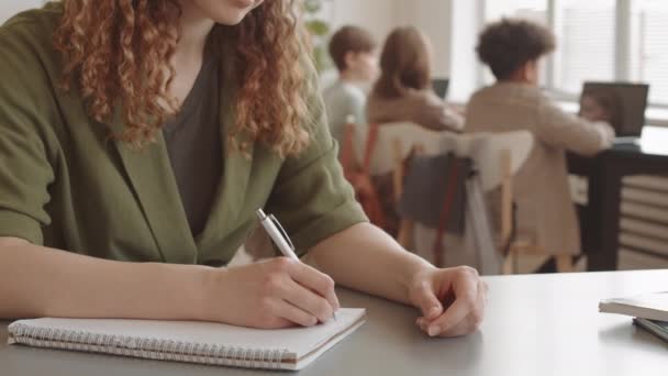 Close Cropped Curly Haired Female Teacher Writing Notebook Sitting Desk — 图库视频影像