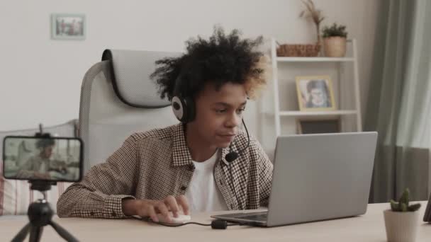 Peito Adolescente Africano Enérgico Usando Fone Ouvido Sentado Mesa Seu — Vídeo de Stock