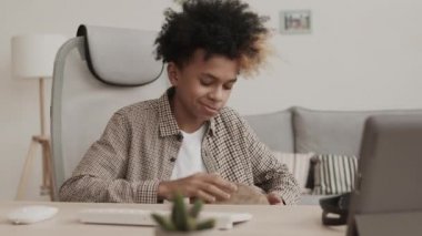 Orta boy Afro-Amerikan ergen çocuk evinde oturmuş, konuşuyor ve djembe oynuyor.