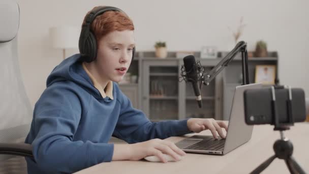 Pasie Rudowłosego Męskiego Influencera Wieku Szkolnym Noszącego Słuchawki Korzystającego Laptopa — Wideo stockowe