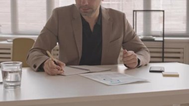 Resmi takım elbise giyen, ofisinde oturan, not defterine yazan, cep telefonuna cevap veren beyaz adamlardan oluşan bir kavis.