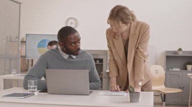 Kafkasyalı genç bir kadının ofiste masasında oturan Afrikalı bir adamla konuşması, meslektaşlarının iş görüşmeleri...