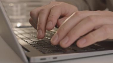 Dizüstü bilgisayarın klavyesine yazı yazan, kalemle notlar yazan tanınmayan bir ofis çalışanının ellerine yakın çekim