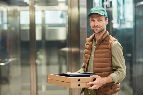 Yemek dağıtan adam pizzayı tutuyor. — Stok fotoğraf