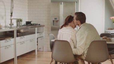Kafkasyalı bir adamın mutfakta kız arkadaşıyla oturduğunu, ona sarıldığını ve kulağına fısıldadığını görünce gülüyor.