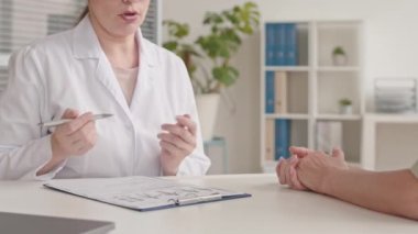 Hasta hastaya teşhis koyan, modern doktor ofisinde el ele oturarak onu destekleyen kadın doktorların orta derecede yavaşlaması.