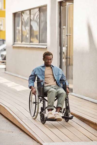 Junger Mann im Rollstuhl fährt Rampe hinunter — Stockfoto