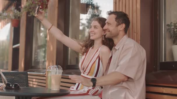 快乐的异性恋白人夫妇在户外餐桌边坐着 用智能手机自娱自乐 玩得开心 — 图库视频影像