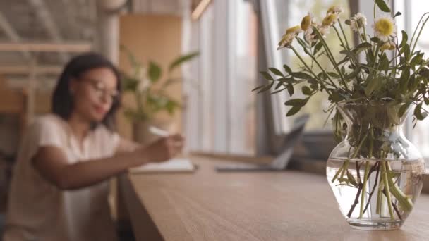 Uzamčená Skleněná Váza Kyticí Heřmánků Stole Kavárně Rozmazaná Žena Pracující — Stock video