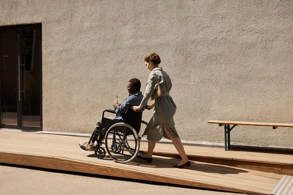 Tolószéket toló nővér fogyatékos férfival — Stock Fotó