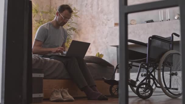 Kompletní Záběr Handicapovaného Bělocha Sedícího Kraji Postele Pokoji Přenosným Počítačem — Stock video