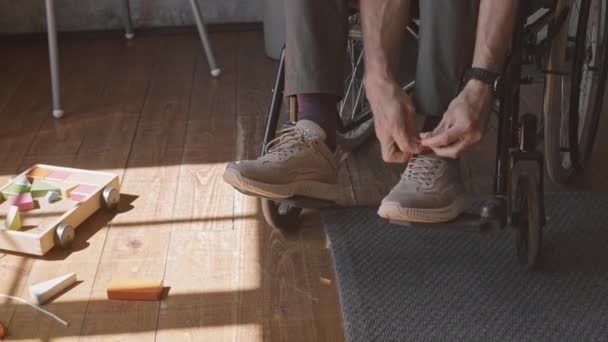 在房间里坐在轮椅上 系鞋带 躺在地板上的木制玩具的白人残疾人弯腰 — 图库视频影像