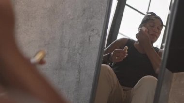 Türban takan, fırçayla makyaj yapan melez bir kadının orta boy yansıması.