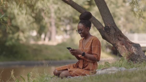 Długie Ujęcie Pięknej Afrykanki Rozmawiającej Przez Telefon Komórkowy Siedzącej Polance — Wideo stockowe