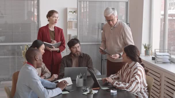 各种年龄的经理们坐着 站在办公室的桌子旁 白天谈生意 他们的速度都很慢 — 图库视频影像