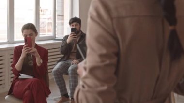 Konferans odasındaki sandalyelerde oturan, akıllı telefonlar ve tablet bilgisayarlar üzerinde tanınmayan bir performans kaydeden orta uzunluktaki çok ırklı dinleyiciler.