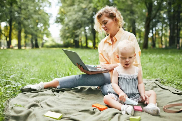 Мать, работающая онлайн в парке — стоковое фото