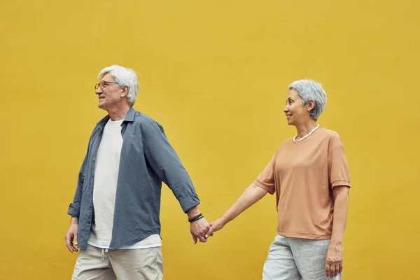 Зріла пара тримає руки на жовтому — стокове фото