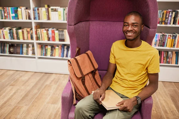 Sorridente giovane uomo nella biblioteca del college — Foto Stock