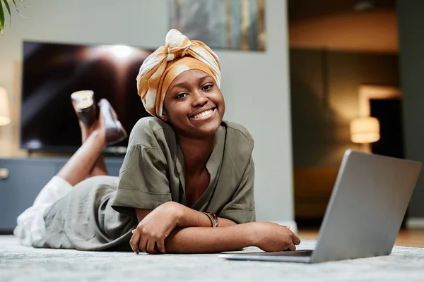 Lachende jonge vrouw met laptop op verdieping — Stockfoto