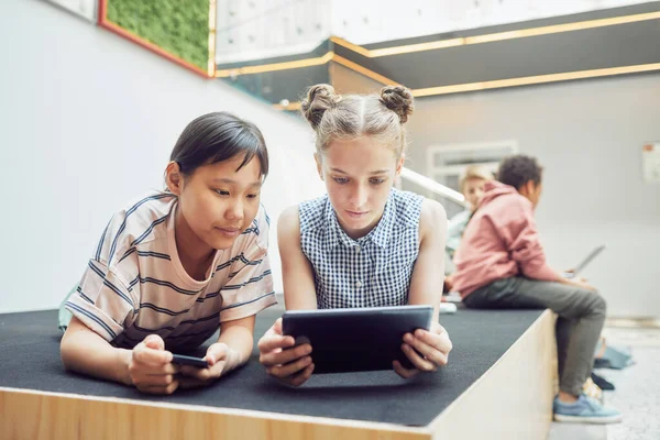 Twee meisjes met behulp van gadgets op school — Stockfoto