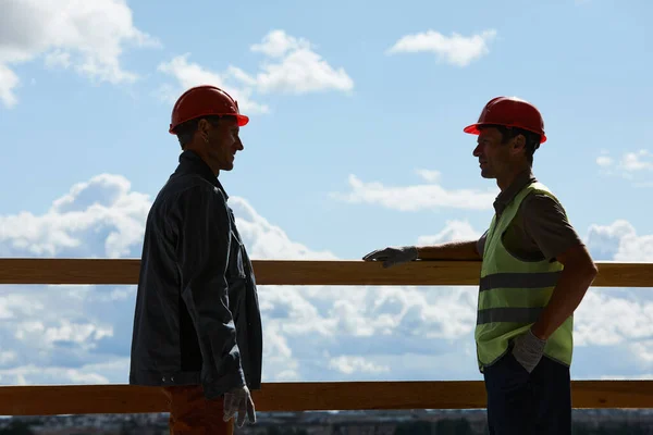 Twee arbeiders aan het kletsen op bouwplaats — Stockfoto
