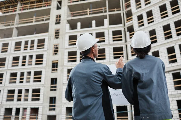 Pracownicy dyskutujący o planach budowlanych — Zdjęcie stockowe