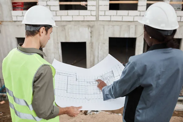 Dwóch pracowników omawiających plany budowy — Zdjęcie stockowe