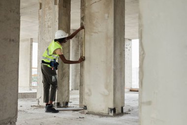 Duvarları ölçen Kadın İnşaat İşçisi