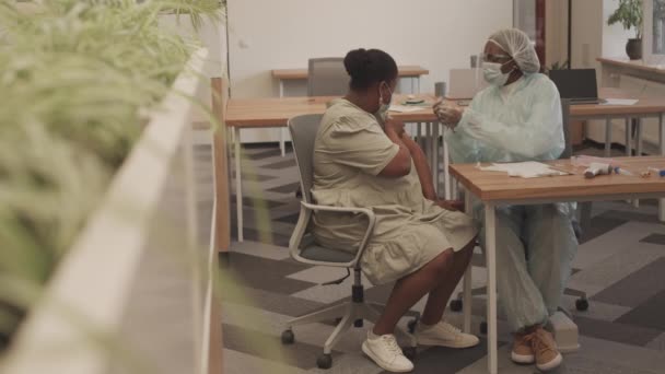 非洲裔美国妇女在现代办公室接种Sars Cov 2疫苗的全照 女性医务工作者在手臂注射疫苗时被射中 — 图库视频影像