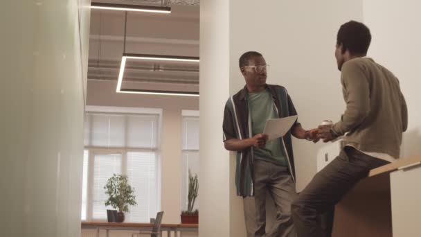 在现代办公室里 两个穿着便衣的黑人年轻人站在复印机旁 边喝咖啡边聊天 中低角镜头 — 图库视频影像