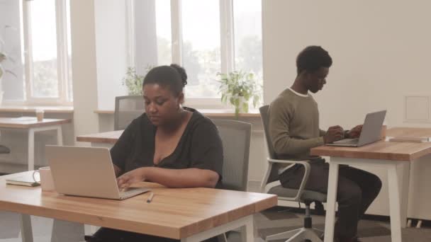 Средний Снимок Молодых Афроамериканцев Работающих Ноутбуках Сидящих Разными Столами Современном — стоковое видео