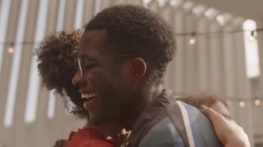 Heyecanlı çok ırklı insanların çatıdaki partide bir araya gelip birbirlerini selamlamaları, kucaklamaları ve gülmeleri.