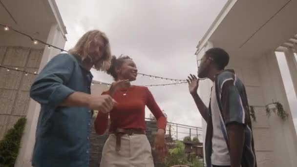 在夏季派对上 年轻迷人的混血女子与两位男性朋友在天台上共舞的中景 — 图库视频影像