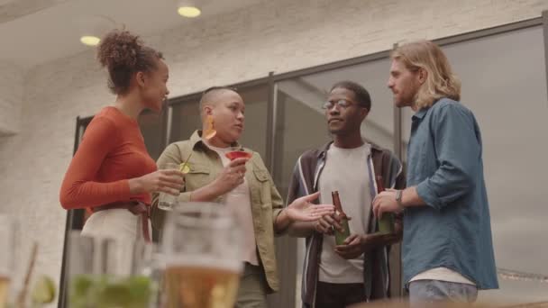 カクテルやビールを楽しむ野外パーティーで会話をする若者の多様なグループの中のショット — ストック動画
