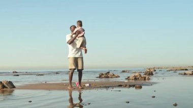 Şefkatli bir Afrikalı-Amerikalı babanın yaz gününü oğluyla plajda geçirmesi ve onu açık mavi gökyüzüne karşı döndürmesi.